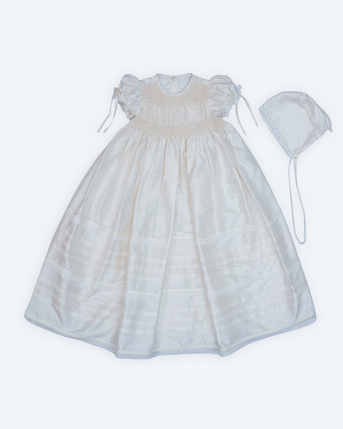 Flat lay front view of white ivory dupioni silk baptism gown with ruffled hem — Josephine Gown Set by Bonbon Rue